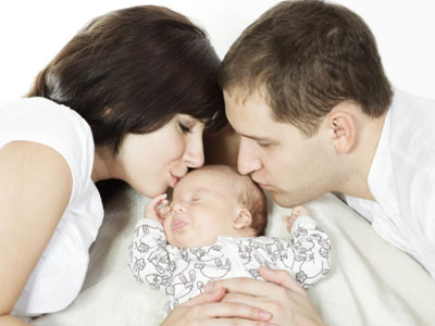 Parents kissing newborn baby over white background. Family love concept.