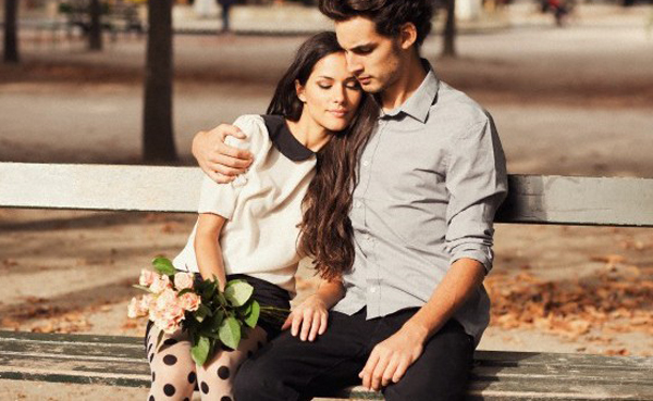 19 Sep 2012, Paris, France --- Portrait of a young couple in Paris, sitting on a bench holding a bouquet --- Image by © Lauren Cooper/Corbis