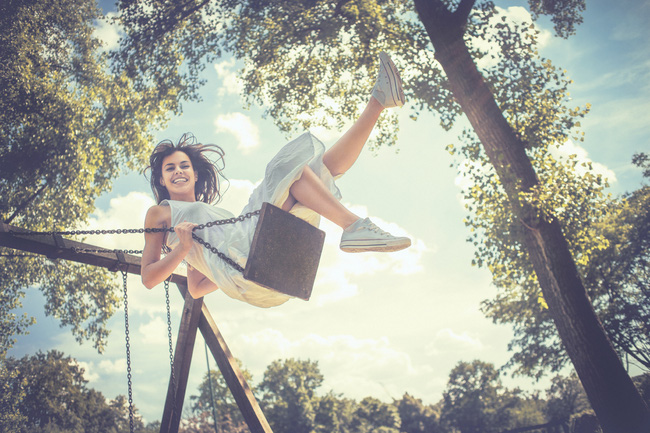 Happy young woman having fun on the swing. Developed from RAW; retouched with special care and attention; Small amount of grain added for best final impression; Ready made for print and web use;